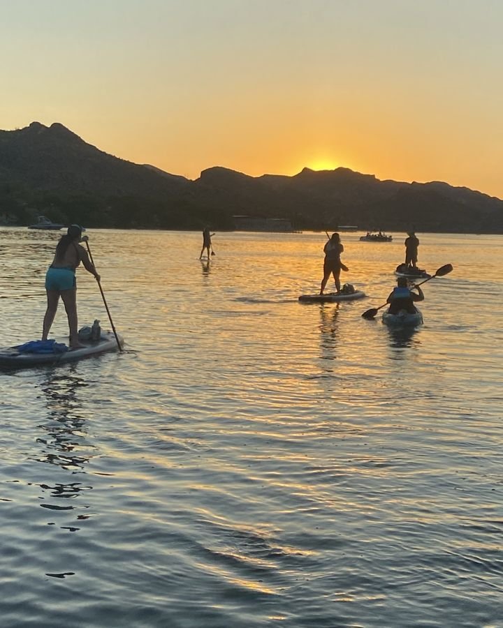 Paddlers on the water at sunset