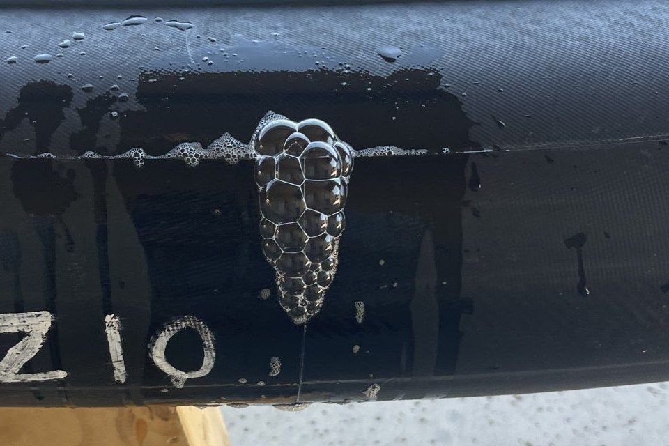 Close-up of soap bubbles growing from a leak on a paddleboard rail seam