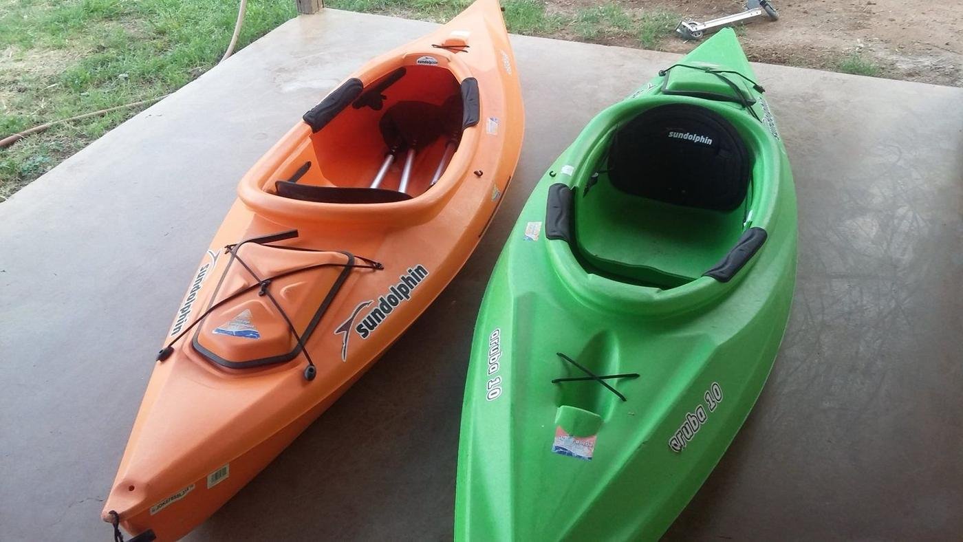 The first two Redline kayaks, an orange and a green Sun Dolphin, in the backyard