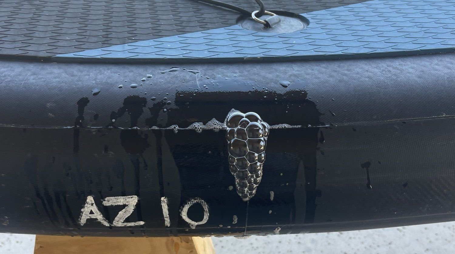 Soapy bubbles growing on the rail of an inflatable paddleboard, showing a leak
