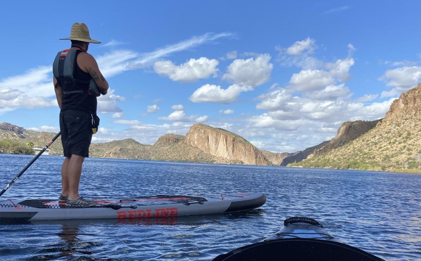 Paddleboarder on a Redline board at Canyon Lake with the canyon walls behind